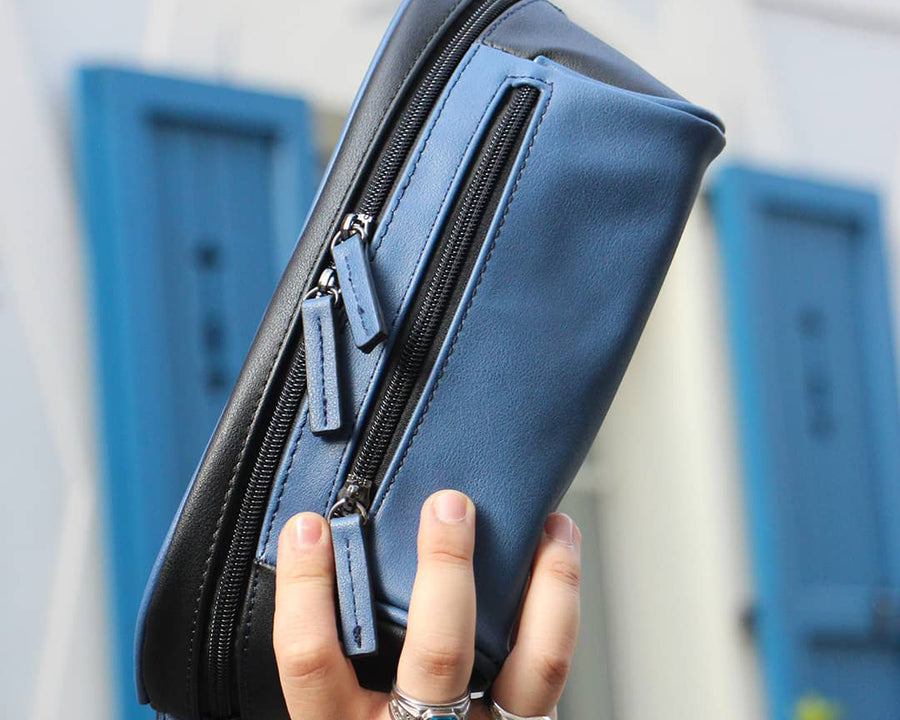 Man in an urban area holding a black and blue streetwear bag from cawa.me