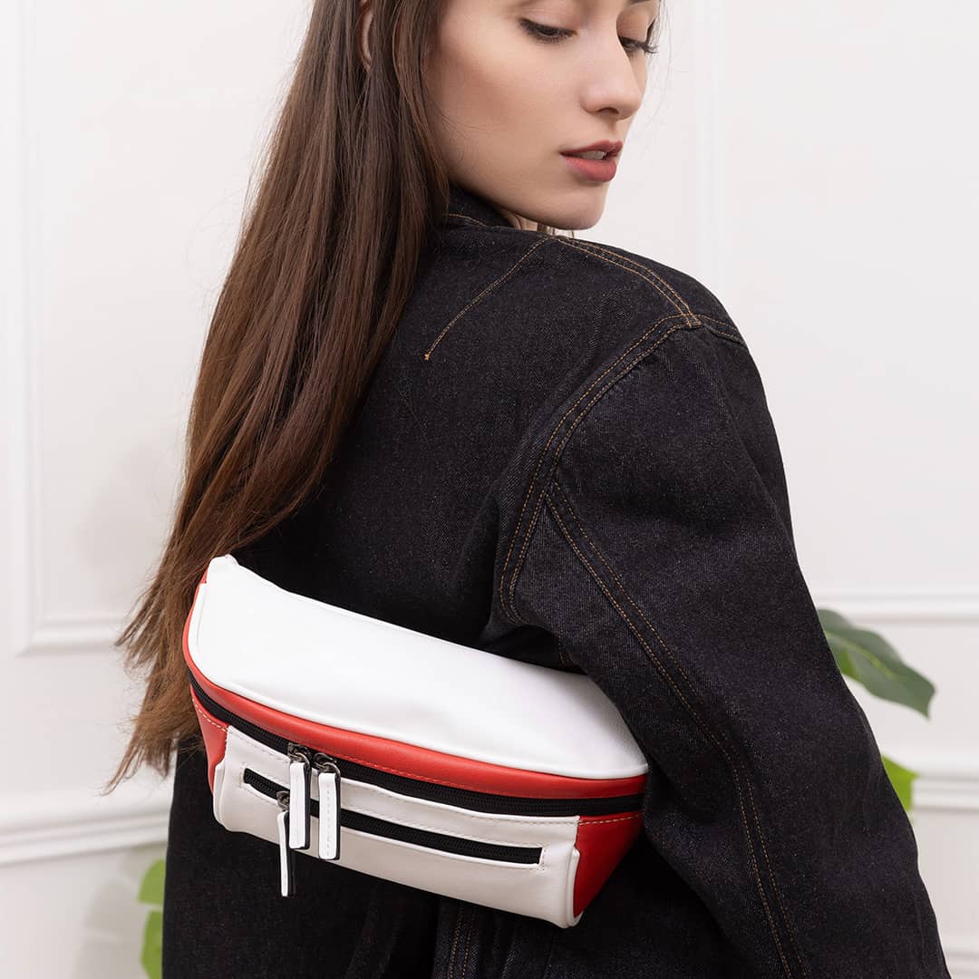 Woman wearing streetwear outfit with a white and red streetwear bum bag from cawa.me in a white room 