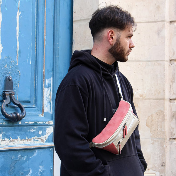 Man in an urban area with a beige and pink streetwear bum bag from cawa.me wearing a streetwear outfit