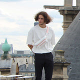 Young man posing in an urban area wearing a white t-shirt and a white streetwear bum bag from cawa.me