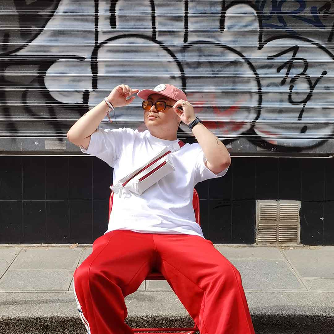 Man in front of a graffiti wall in a sportswear outfit with a white streetwear bum bag from cawa.me